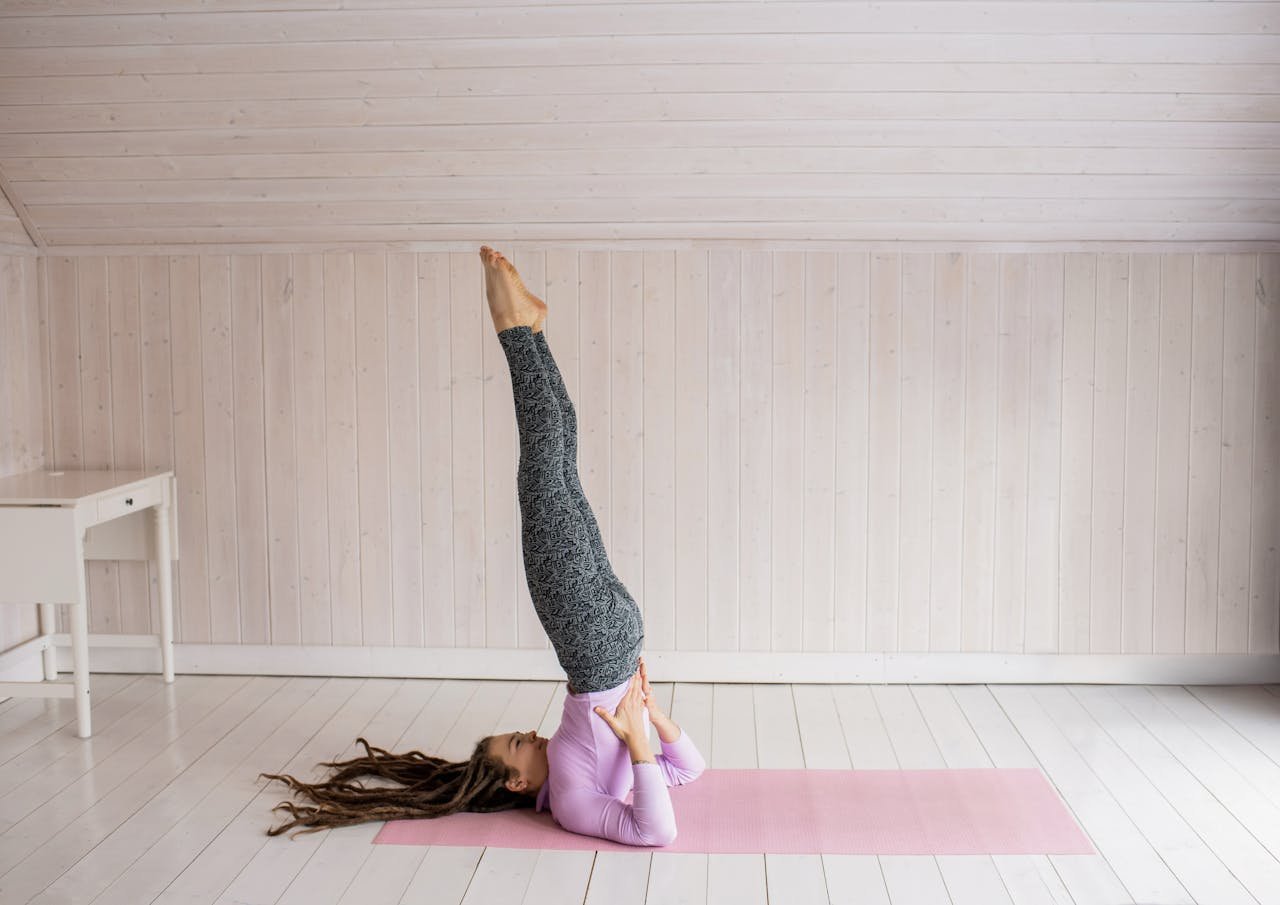 projects-header Woman in a yoga pose on a pink mat indoors, demonstrating flexibility and balance.